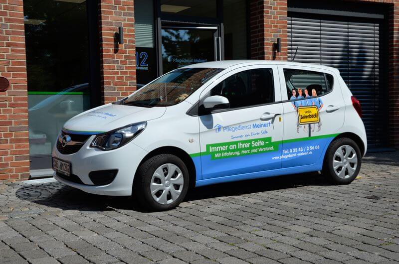 Ein Opel Corsa mit Werbung vom Pflegedienst Meinert steht vor dem Büro